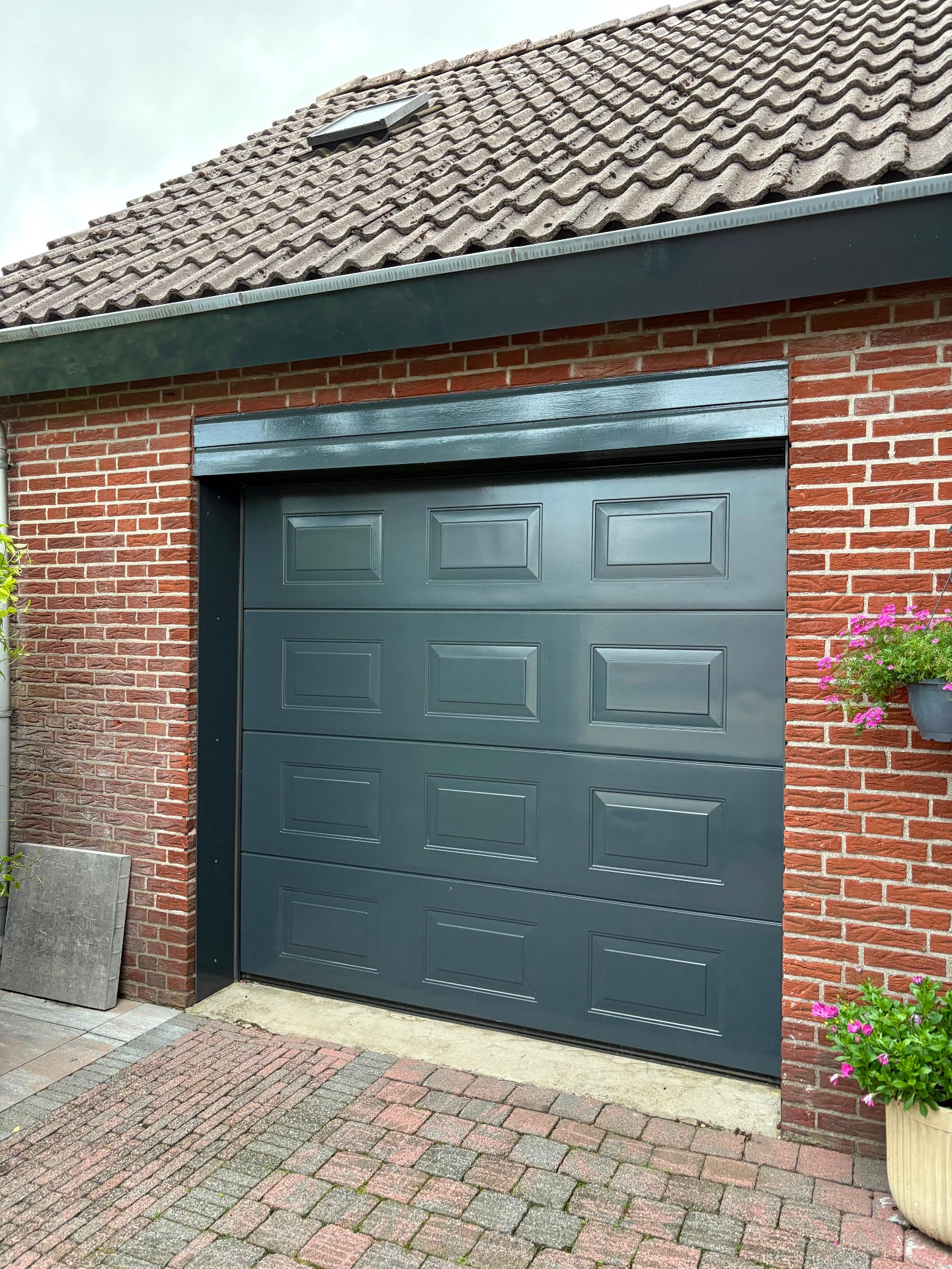 Antraciet garagedeur netjes afgewerkt in de gevel
