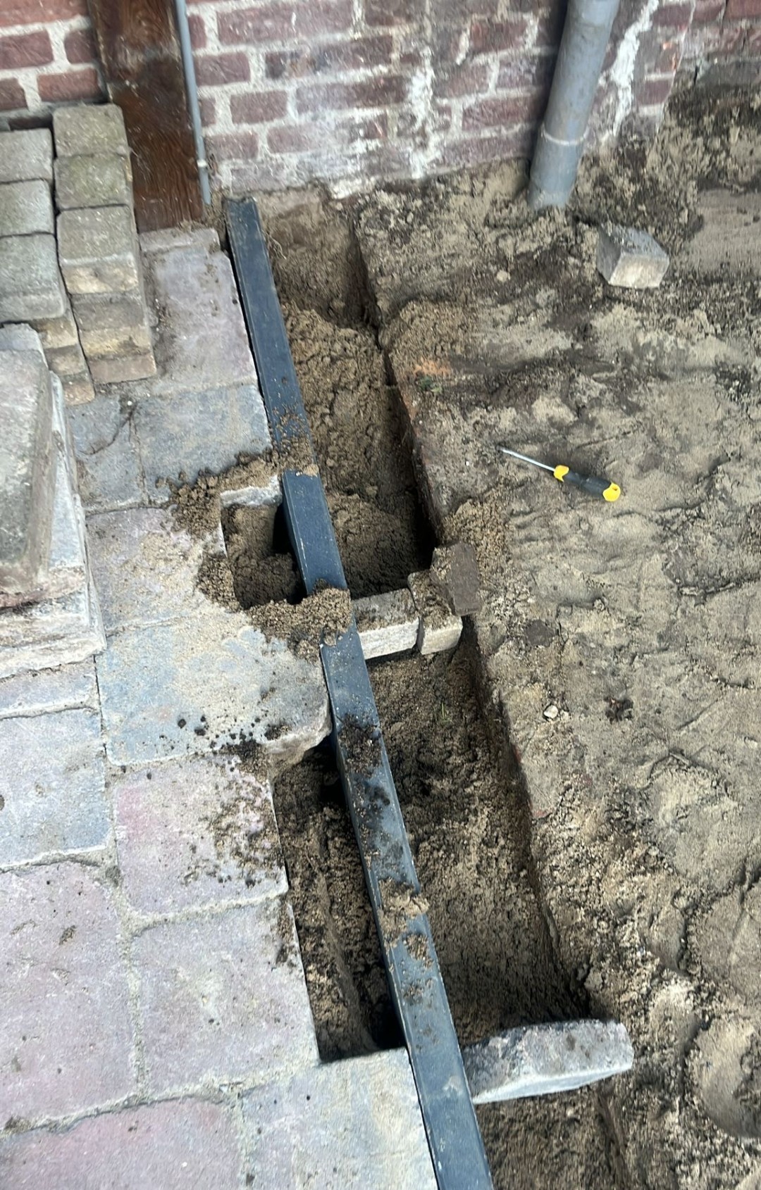 Grondwerk: sleuf gegraven langs de bestrating