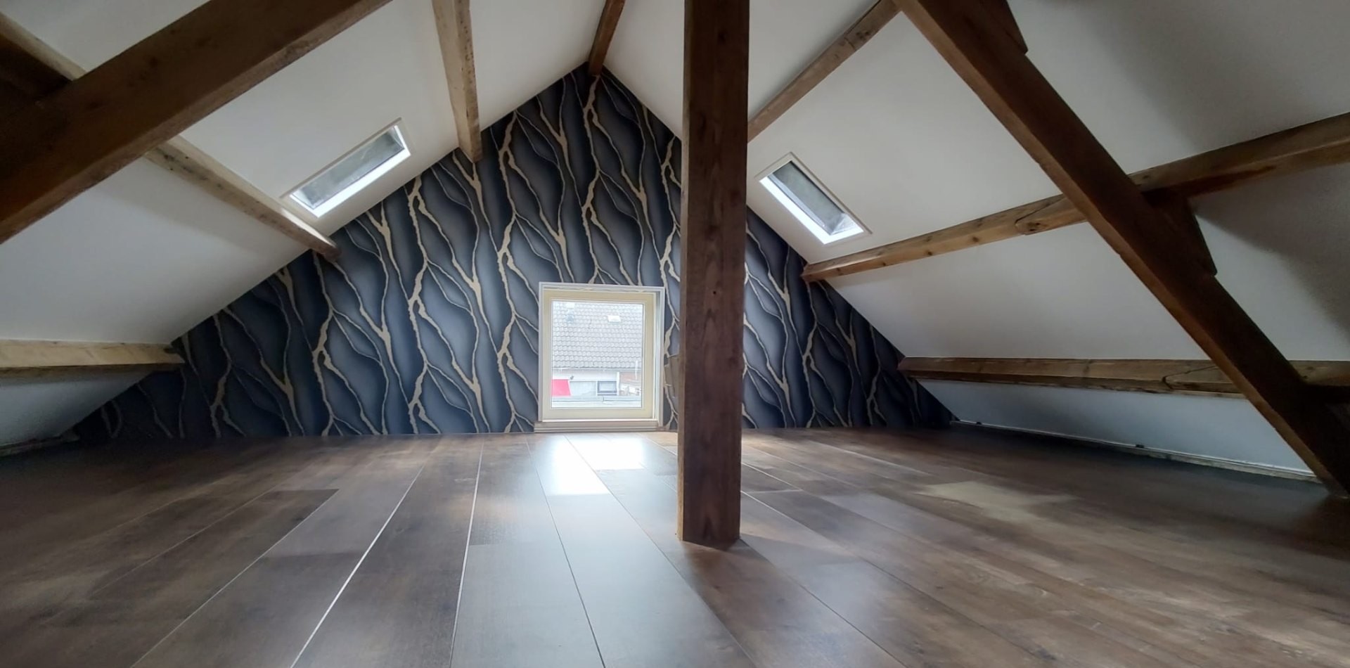 Afgewerkte zolder met behang, dakramen en houten balken
